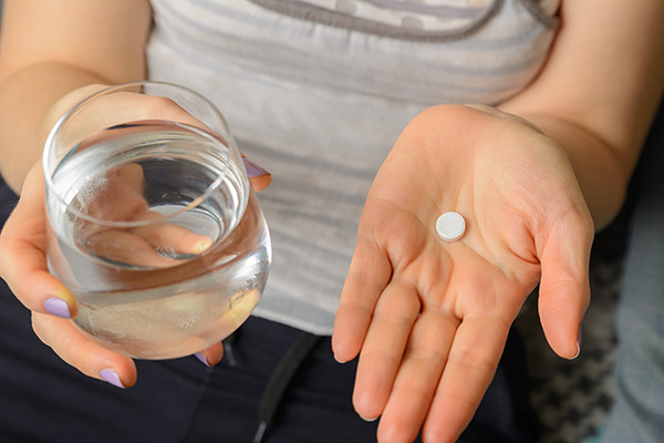 A woman with a pill and a glass of water in hand